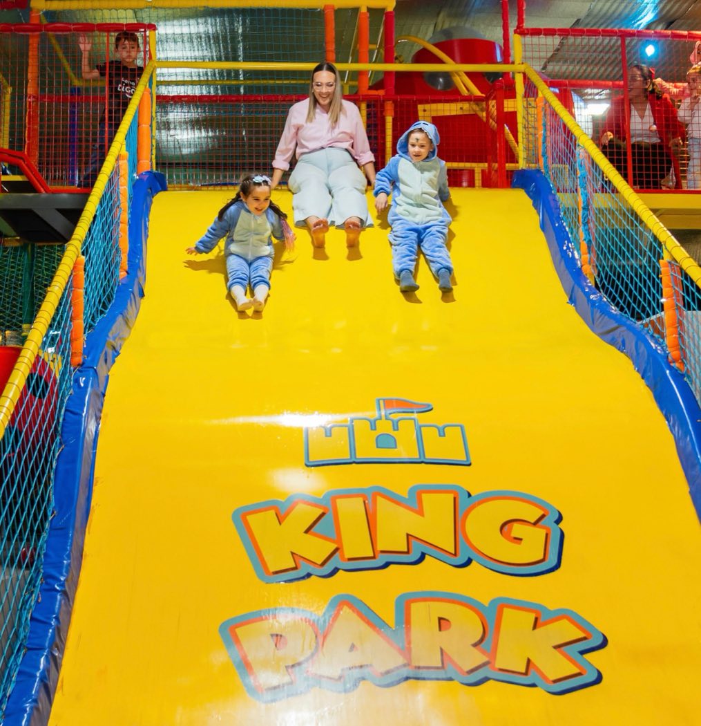 Mamá y dos chicos bajando por el tobogán gigante de King Park
